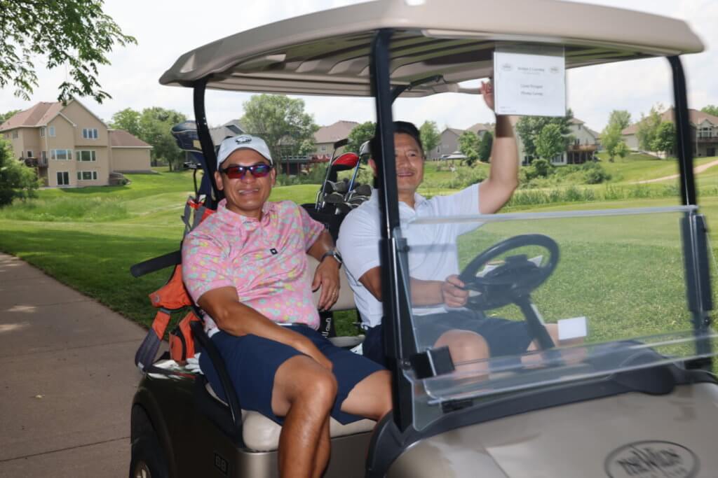 Two golfers pose for a photo sitting in their carts on the Wilds Golf Club course at the 4th Annual Bridges to Learning Golf Tournament, Prior Lake Minnesota. Raising funds to educate and care for poor children in Vietnam.
