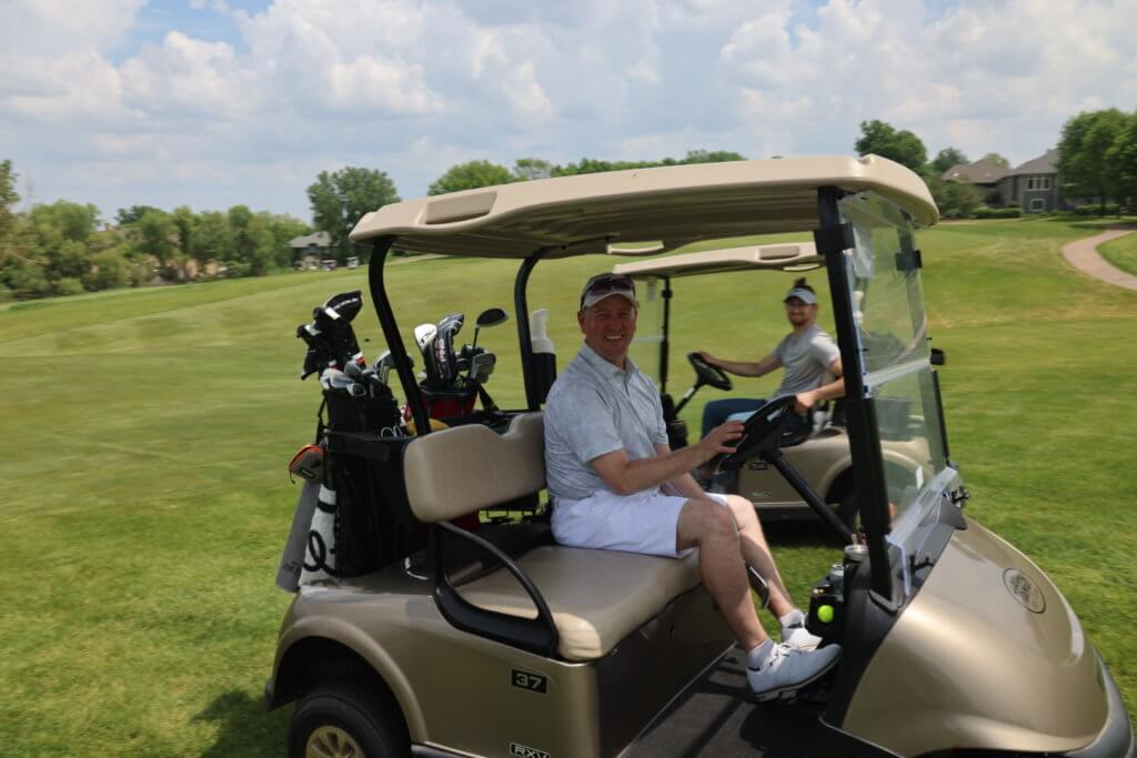Two golfers pose for a photo sitting in their carts on the Wilds Golf Club course at the 4th Annual Bridges to Learning Golf Tournament, Prior Lake Minnesota. Raising funds to educate and care for poor children in Vietnam.