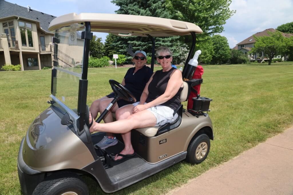 Two volunteers relax in a golf cart before heading out to the Wilds Golf Club course at the 4th Annual Bridges to Learning Golf Tournament, Prior Lake Minnesota. Raising funds to educate and care for impoverished children in Vietnam.