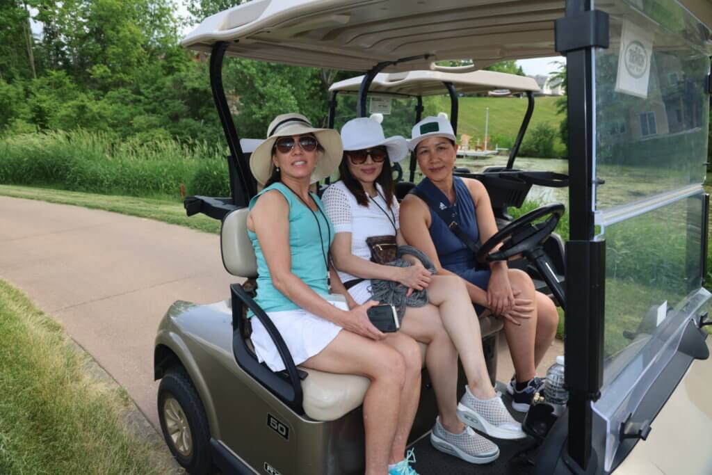 Three volunteers pose for a photo sitting in their carts on the Wilds Golf Club course at the 4th Annual Bridges to Learning Golf Tournament, Prior Lake Minnesota. Raising funds to educate and care for poor children in Vietnam.