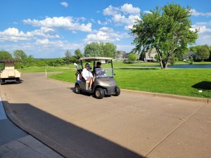 Golfers driving cart out to course on a beautiful day at the Wilds Golf Club for Bridges to Learning Tournament.