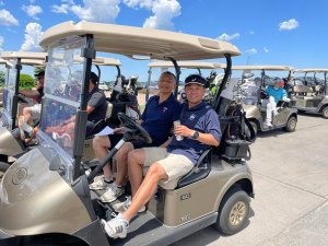 Smiling golfers waiting in carts before heading out to the Wilds Golf Course to start Bridges to Learning charity golf tournament.