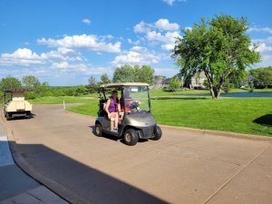 Golfers driving cart out to the Wilds Golf course for Bridges to Learning Golf Tournament.