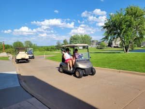 Golfers waving and driving a cart out to the gorgeous Wild Golf Club course to start the 2022 Bridges to Learning Golf Tournament. Raising money to support poor children in Vietnam.