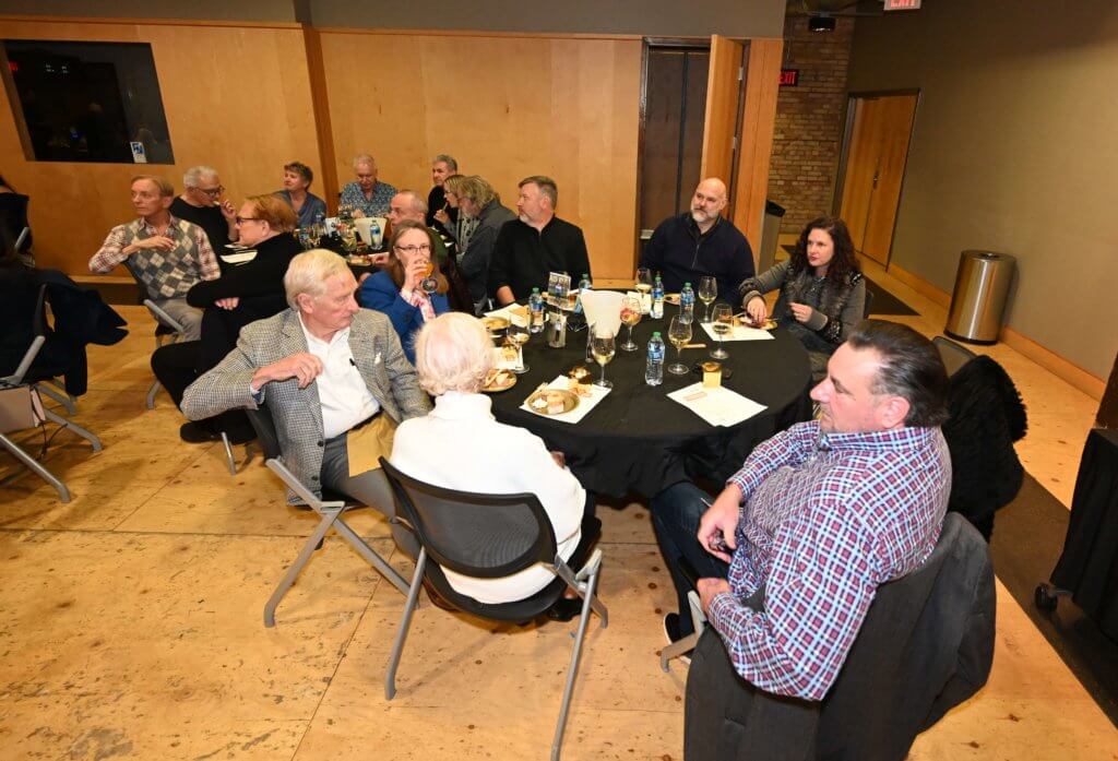 Seated 2022 Wine Tasting guests listen to wine expert, while enjoying food and wine. Bridges to Learning, Minnesota nonprofit.