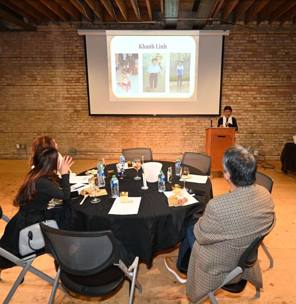 Seated 2022 Wine Tasting guests listen to wine expert, while enjoying food and wine. Bridges to Learning, Minnesota nonprofit.