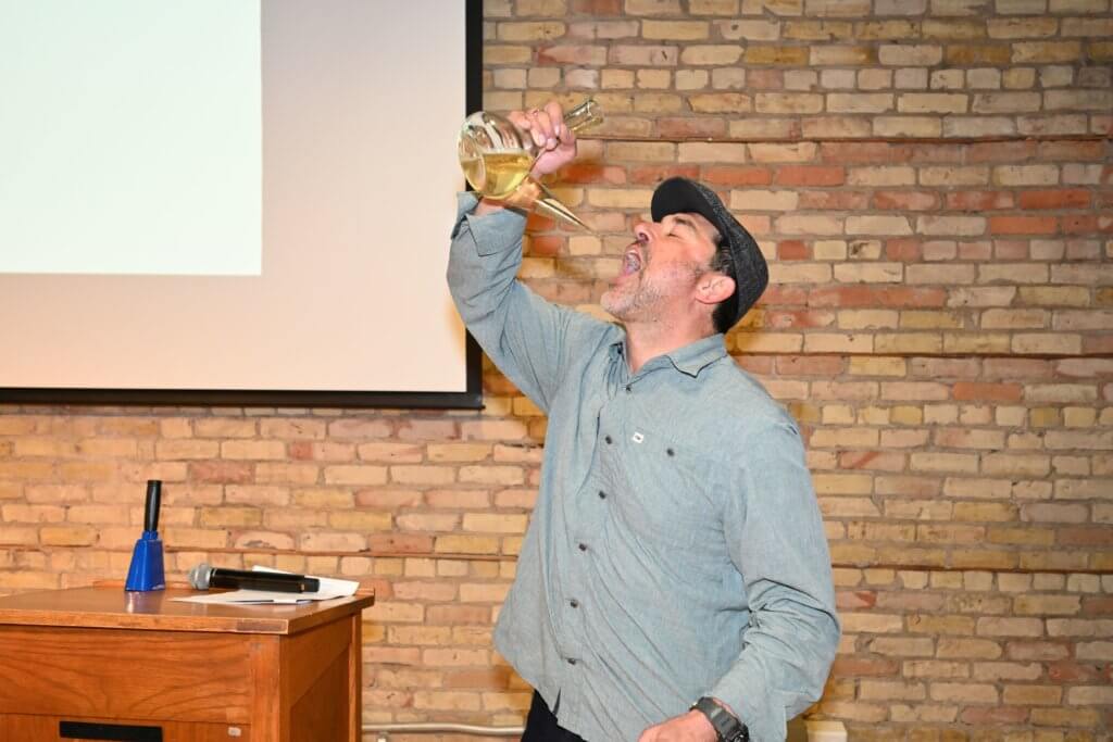 Joe Kotnik, owner Rootstock Wine Co. demonstrates his porron expertise at Bridges to Learning 2022 Wine Tasting. Nonprofit raising funds to educate poor children in Vietnam.
