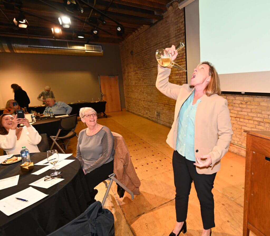 Bridges to Learning 2022 Wine Tasting guest demonstrates her skill with porron. Nonprofit raising funds to educate poor children in Vietnam.