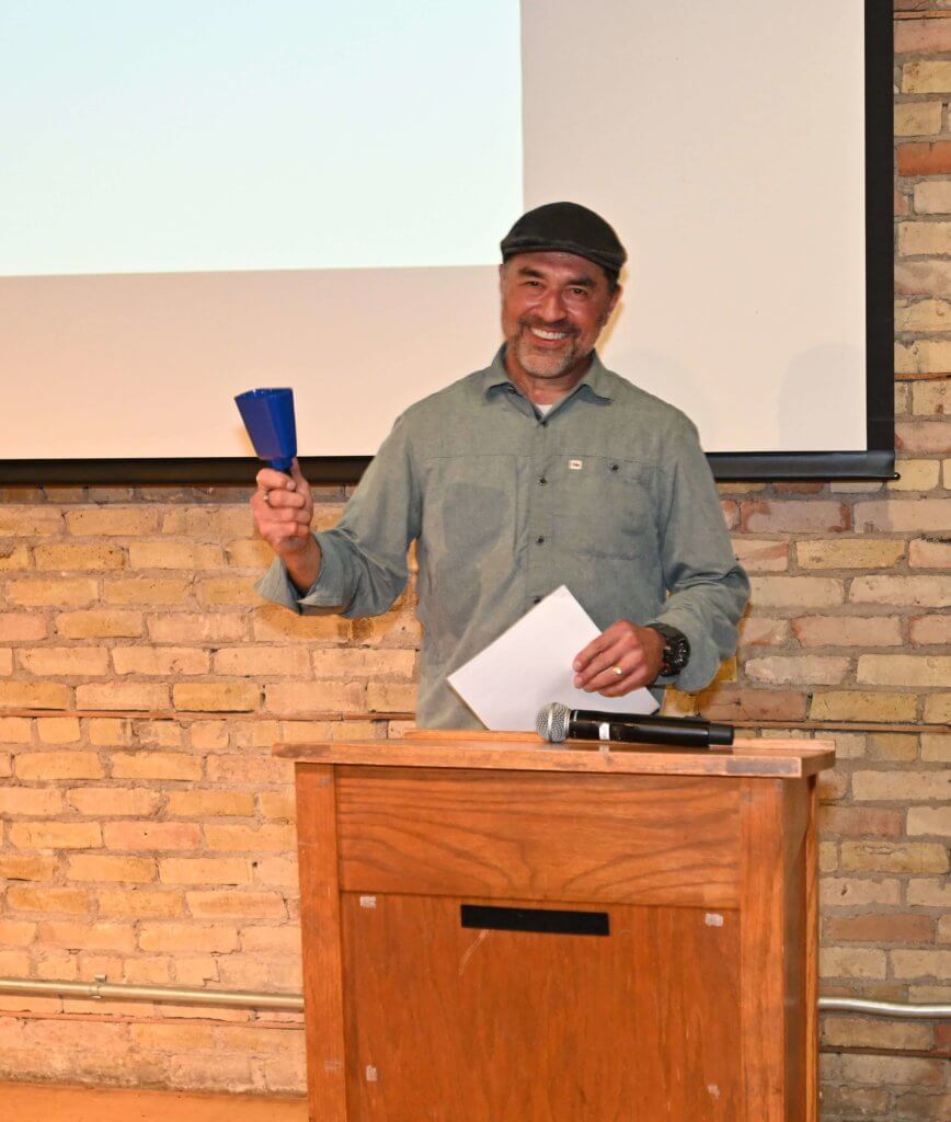 Rootstock Wine Co. owner rings the cow bell to get the attention of guests at 2022 Wine Tasting for nonprofit Bridges to Learning.
