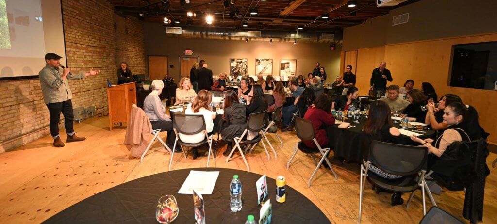 2022 Wine Tasting guests listen to Rootstock Wine Co. owner introduce a type of wine. Bridges to Learning nonprofit fundraiser. Minneapolis Minnesota.