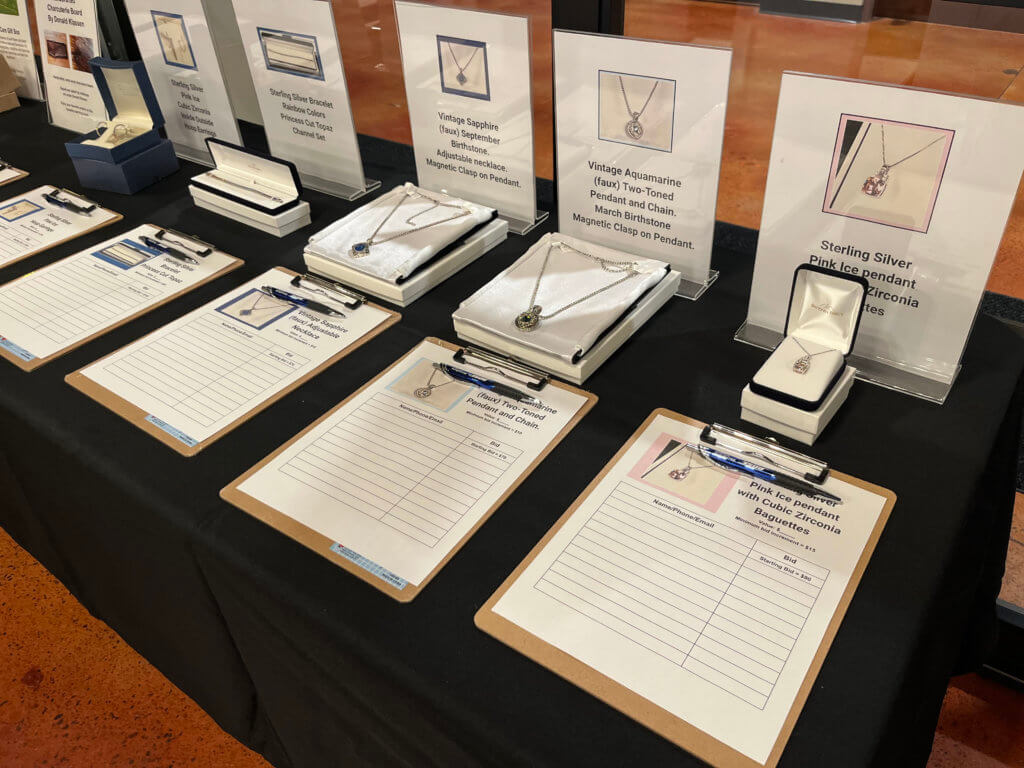 Table with jewelry donated by Diamonds Direct (Minnesota) for the silent auction at the 2023 Bridges to Learning Wine Tasting fundraiser. Nonprofit raising funds to educate and nourish poor children in Vietnam. South Lyndale Liquors event space.