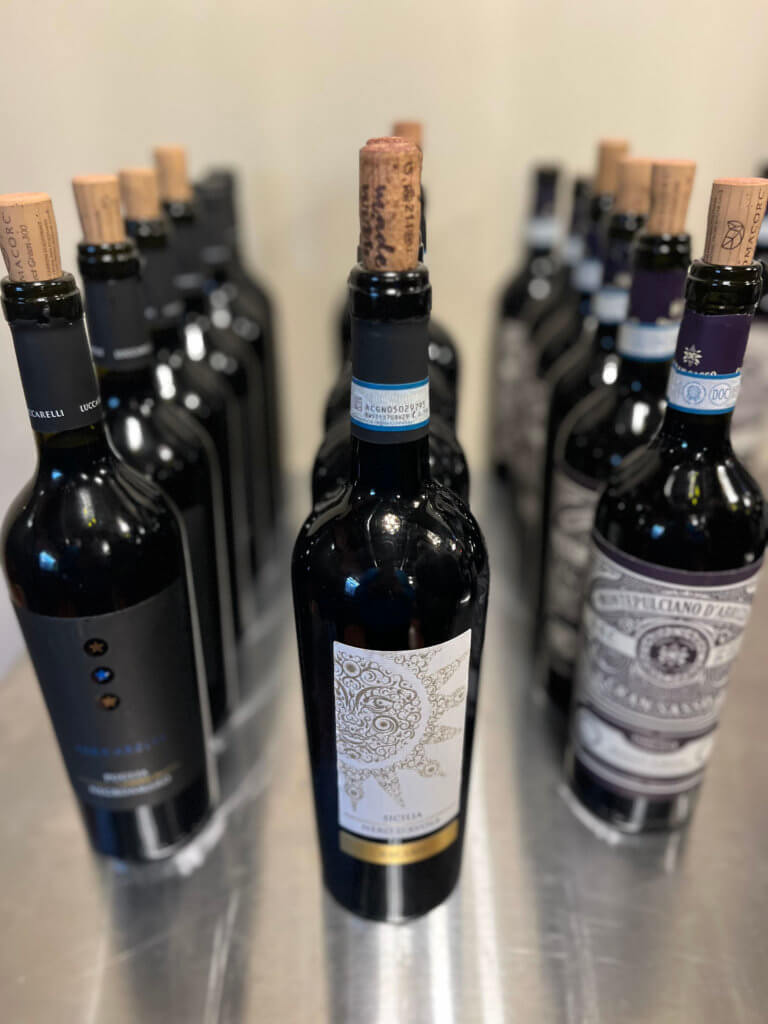 Rows of wine bottles ready to go for the 2023 Bridges to Learning Wine Tasting fundraiser. Nonprofit raising funds to educate and nourish poor children in Vietnam. South Lyndale Liquors event space.