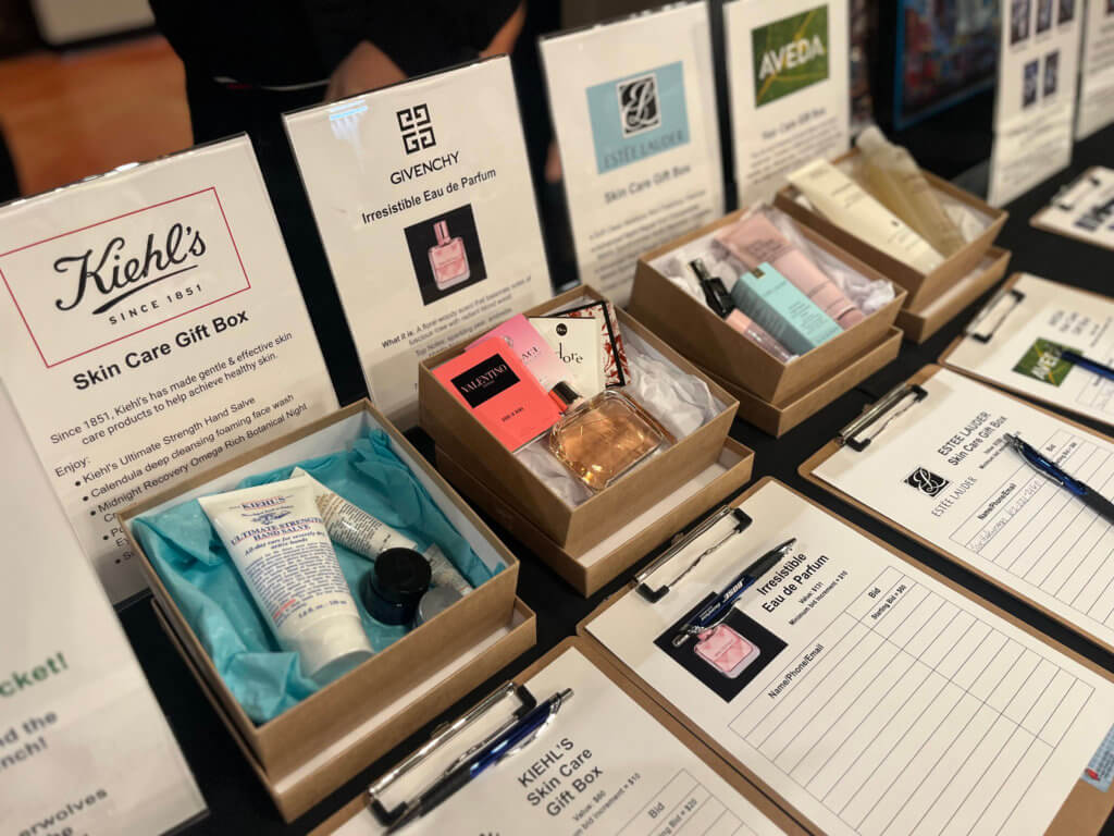 Table with silent auction items for the 2023 Bridges to Learning Wine Tasting fundraiser. Nonprofit raising funds to educate and nourish poor children in Vietnam. South Lyndale Liquors event space.