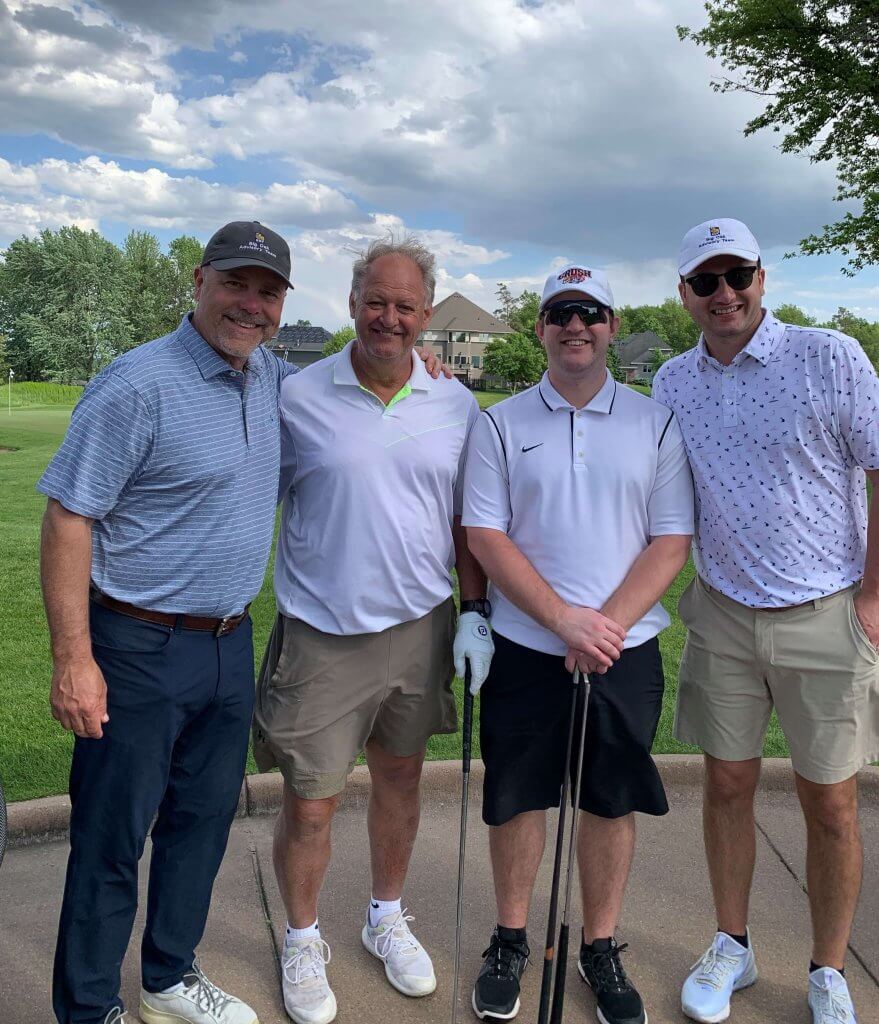 Bridges to Learning 3rd Annual Charity Tournament at The Wilds Golf Club, Prior Lake Minnesota. Four smiling golfers standing by the course. At tournament to raise funds for schools for impoverished children in Vietnam.