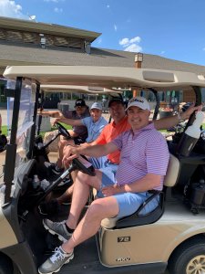 Smiling golfers sitting in carts waiting to head out to the Wilds Golf Course to start the 2022 Charity Tournament for Bridges to Learning. Minnesota.