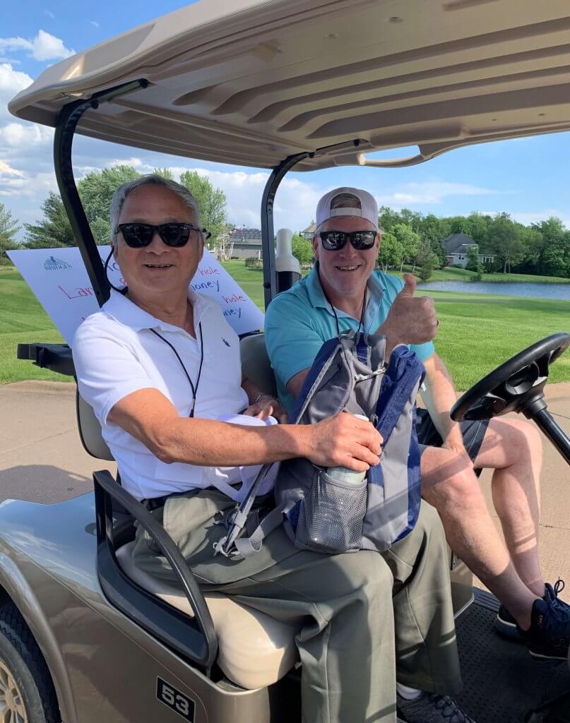 Bridges to Learning 3rd Annual Charity Tournament at The Wilds Golf Club, Prior Lake Minnesota. Happy volunteers in golf cart ready to go to the hole and start the games, raising funds for schools for impoverished children in Vietnam.