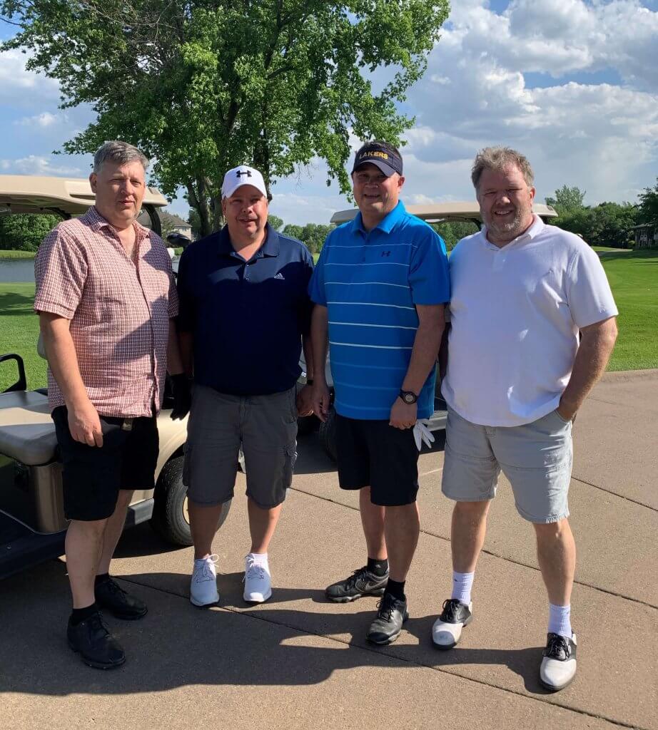 Bridges to Learning 3rd Annual Charity Tournament at The Wilds Golf Club, Prior Lake Minnesota. Four smiling golfers posing by their cart. At tournament to raise funds for schools for impoverished children in Vietnam.