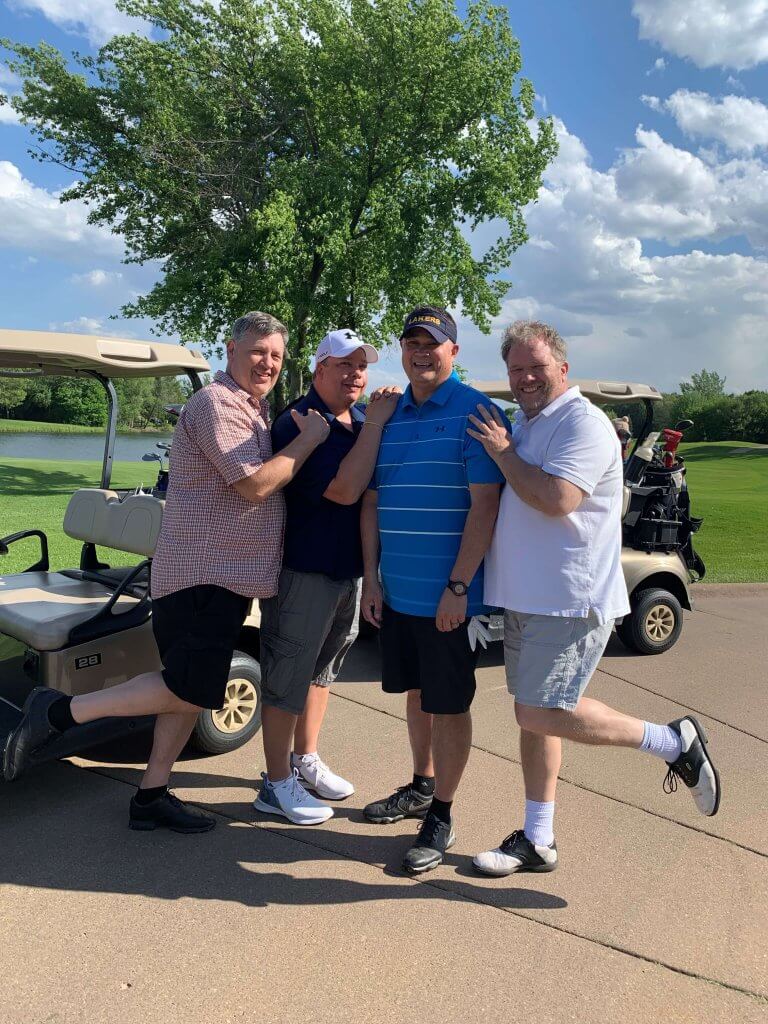 Bridges to Learning 3rd Annual Charity Tournament at The Wilds Golf Club, Prior Lake Minnesota. Four smiling golfers goofing off by their cart. At tournament to raise funds for schools for impoverished children in Vietnam.