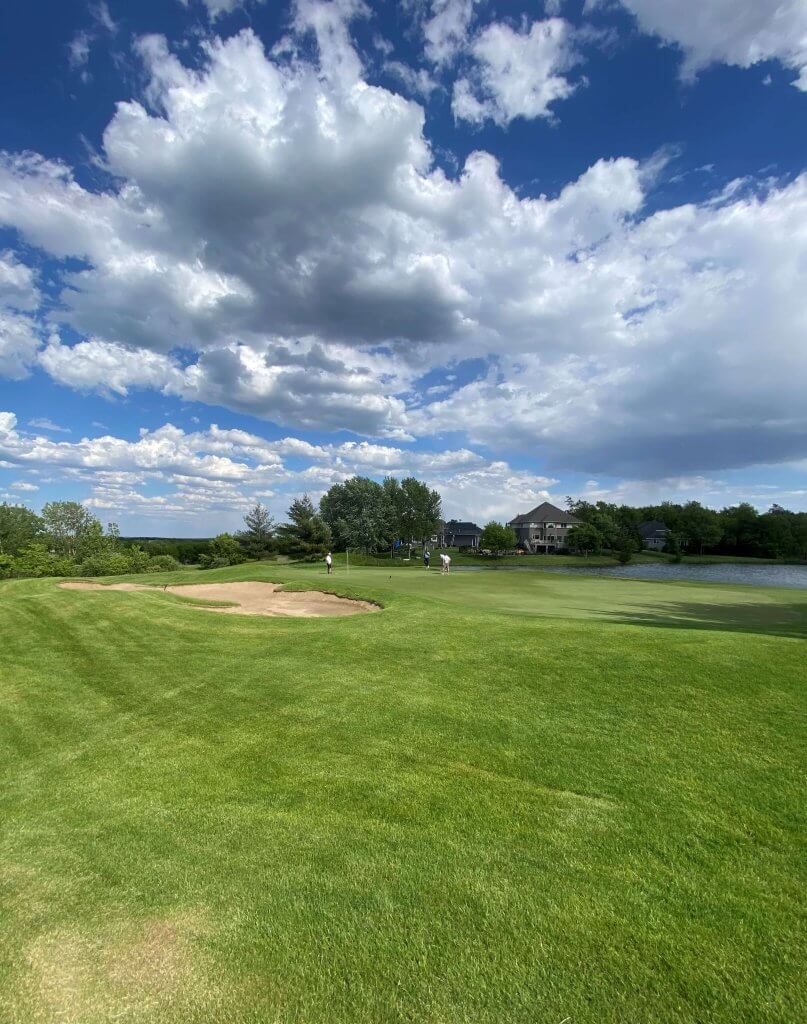 Bridges to Learning 3rd Annual Charity Tournament in Prior Lake Minnesota. Beautiful landscape of the Wilds Golf course with cloudy blue sky on a windy day. Golfers playing in the distance.  At tournament to raise funds for schools for impoverished children in Vietnam.