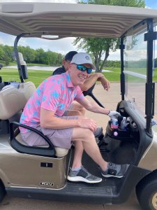 Smiling golfer sitting in cart waiting to start the 3rd Annual Bridges to Learning Golf Tournament at the Wilds Golf Club in Minnesota. 2022.