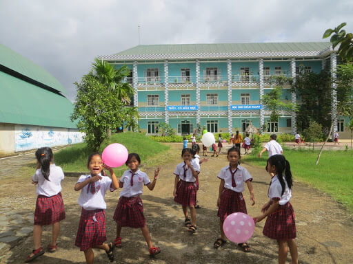 Young children in uniform playing outside of Viet Anh Primary School. Da Teh province Vietnam.