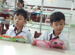 Young boys in school uniforms reading children's books.