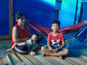 Young child, baby and mom, in home with plastic sheeting walls. Vietnam. Viet Anh Primary School Da Teh province Vietnam.