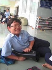 Boy sitting on floor and smiling. Wearing his glasses.